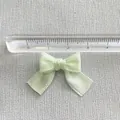 Close-up of small light green satin bow accessory with ruler showing 3cm width scale - Light Green