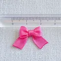 Detail view of pink satin ribbon bow with ruler showing 25mm size for DIY accessories - Hot Pink