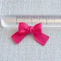 Detail shot of 20mm rose pink satin ribbon bow showing size measurement with a ruler - Rose Pink