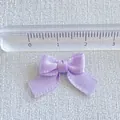 Detailed view of a 2.5cm light purple satin ribbon bow showing texture and size with a ruler - Light Purple
