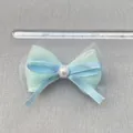 Detail van blauwe satijnen strik met parel en tule, toont breedte van 8,5cm op liniaal - Muntgroen Pailletten Tule Parel Stijl (5)