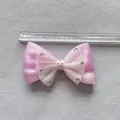 Primer plano de un lazo de malla rosa con diamantes y lunares junto a una regla graduada - Estilo Rosa Capas Malla Lunares (4)