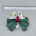 Detail shot of Christmas bow hair clip with faux pearl pendant measuring 6.5cm wide - White Ribbon Christmas Bell Pattern