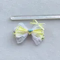 Dettaglio fiocco giallo da 8,5cm con pizzo bianco e cristallo centrale a forma di cuore - Giallo