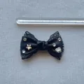 Dettaglio di un fiocco in pizzo nero da 7 cm con strass lucidi e raso morbido - Nero