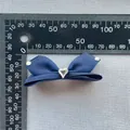 Dettaglio ravvicinato del fiocco in raso blu con strass a forma di cuore al centro - Blu scuro
