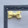 Detail view of yellow satin bow accessory with heart crystal and measurement scale - Heart Satin Style