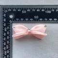 Dettaglio fiocco in raso rosa con strass a cuore su sfondo con righello graduato - Rosa