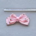Close-up of pink rhinestone bow hairclip with ribbed texture showing 8cm length scale - Pink