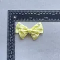 Close-up of a light yellow satin bow accessory with white pearls and measuring scale - Pearl Decor Satin Style