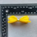 Dettaglio del fermaglio a fiocco in raso giallo con strass a cuore di misura 6,5 cm - Giallo