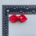Detailed view of red grosgrain ribbon bow with star rhinestone on measuring scale - Red