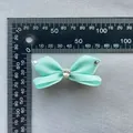 Dettaglio di un fiocco in nastro verde menta da 5cm con strass a cuore e righello di misurazione - Verde Menta