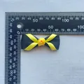 Dettaglio di un fiocco in nastro nero e giallo da 45 mm con misura su un righello - Giallo Brillante E Nero