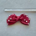 Detail of burgundy grosgrain ribbon bow with rhinestones next to a measuring ruler - Burgundy