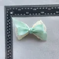 Detailansicht einer minzgrünen Doppelsatin-Schleife mit Spitze und dem Messlineal - Mintgrün