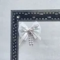 Detailansicht der weißen Chiffon-Schleife mit Perlenquasten und Maßband für die Größe - Weiß