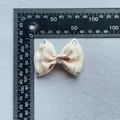 Macro detail of a 60mm beige handmade bow accessory with sparkling heart rhinestone and gems - Beige Textured Style (8)