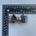 Detail view of a handmade black satin bow hair clip with houndstooth pattern base and ruler - Tri-Color Houndstooth Style (8)