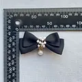 Detail einer schwarzen Schleife mit Perlenkette und einem Tropfenperlen-Anhänger - Schwarz