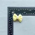 Detailed view of a light yellow ribbon bow with pearl bead and measurement scale - Artificial Pearl Light Yellow Grosgrain Bowknot (7)