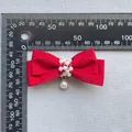 Detail einer roten Satin-Schleife mit weißen Perlen und einem vertikalen Perlenanhänger - Rot