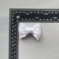 White double-layered satin ribbon bow 40mm x 30mm measurement on a textured grey background - White