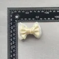 Detailed top view of a 6cm beige satin bow with lace and rhinestones next to a ruler - Beige