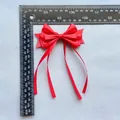 Détail d'un nœud en satin rouge avec de longs rubans à côté d'une règle graduée - Style Multicouche Rouge (7)