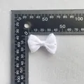 Detalle de un pequeño lazo de malla blanca con pedrería plateada sobre una regla de medida - Malla Blanca Con Brillantes (14)