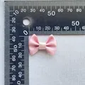 Macro view of a 3cm pink satin ribbon bow accessory displayed on a white textured cloth - Pink (4)