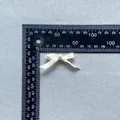 Detail shot of a ribbon bow with pearl center next to a ruler for 4cm size reference - Cream White (9)