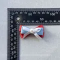Detalle de lazo de cinta de tres capas de 5 cm con perla junto a una regla graduada - Red Blue White