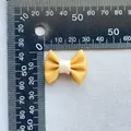 Macro shot showing size measurement of 3cm yellow fabric bow for DIY crafts and decor - Yellow (5)