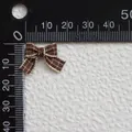 Vista macro de un mini lazo de cuadros marrón que muestra el tamaño de 18mm en regla - Cuadros Marrón y Beige