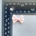 Macro view of a 3cm baby pink satin ribbon bow accessory with a measuring scale - Light Pink (15)