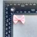 Macro detail of a 25mm pink satin ribbon bow accessory with measurement scale - Pink (16)