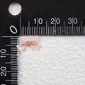 Detailed macro view of a 15mm light pink satin ribbon bow next to a measuring ruler scale - Lotus Pink Style