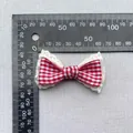 Detail of red gingham plaid fabric bow with lace trim showing 5cm size on a scale - Large Red White Gingham With Lace