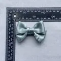 Detailed size measurement of a 85mm sage green satin ribbon bow accessory with a ruler - Grey Green