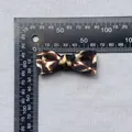 Detalle de un lazo de tela con estampado de leopardo de 45 mm sobre una regla - Estilo Leopardo Pequeño