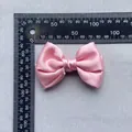 Detailed view of a pink satin decorative bow with dimensions shown on a ruler - Pink