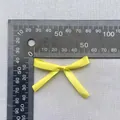 Makro-Detail einer 45mm gelben Satin-Schleife mit Messwerkzeug für Skala und Größe - Gelb (6)