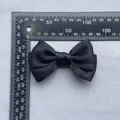 Detail view of a 9.5cm black satin bow accessory with ruler showing precise dimensions - Black