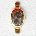 Vista dettagliata di un orologio ovale dorato con quadrante grigio scuro e numeri romani - Stile Ovale Multistrato Oro Quadrante Grigio Scuro