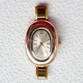 Vista macro del quadrante ovale in oro rosa con numeri romani e cinturino a maglie - Stile Ovale Oro Rosa Numeri Romani