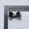 Detail of a double-layered Morandi bow accessory showing 8.5cm measurement on a scale - Black and Silver Grey (5)