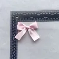Detailed view of a 7.5cm pink satin ribbon bow with measuring ruler for accessory sizing - Pink (6)