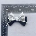 Detalle de un lazo de satén hecho a mano con rosa blanca y perlas para decoración DIY - Gris Plata
