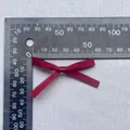 Detail einer 50mm weinroten Satinschleife mit seidiger Textur und Größenmaß auf Lineal - Weinrot (17)